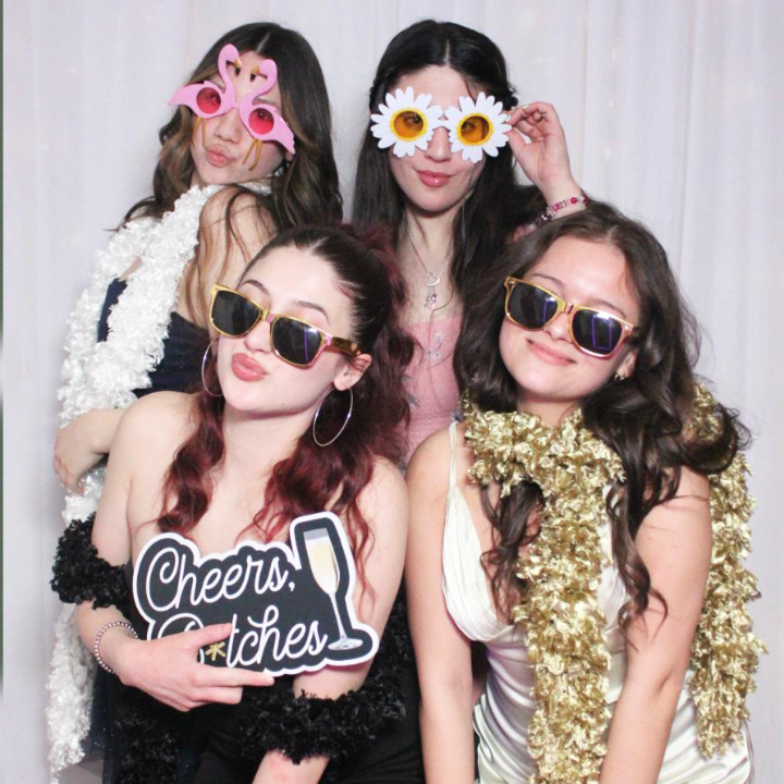 Group of friends posing in a photo booth wearing fun props, novelty sunglasses, and party accessories.