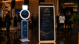 Reception area at Elevate Summit 2026 with dark elegant signage and warm lighting; people networking in background.
